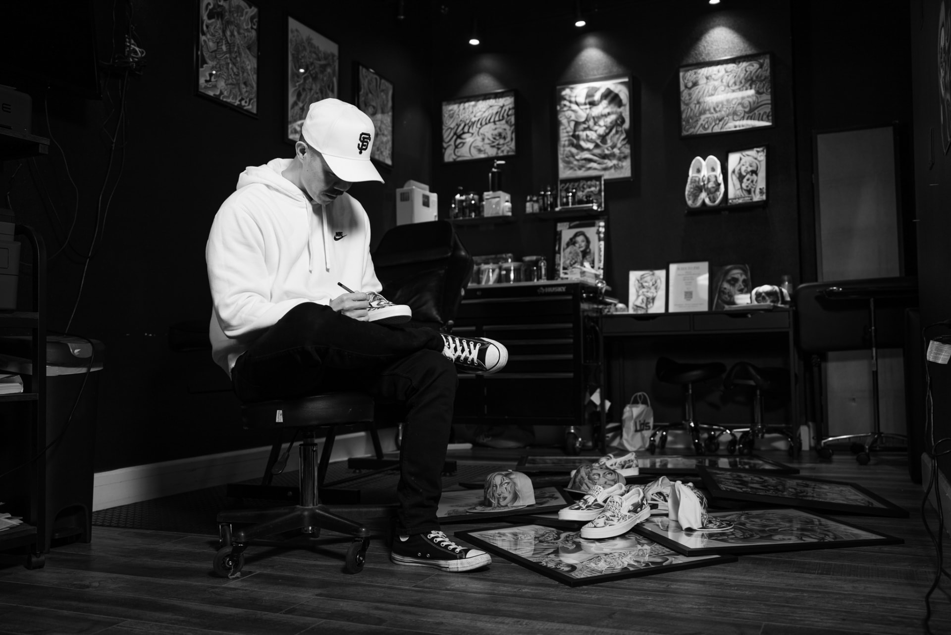 Black-and-white photo of an artist painting sneakers in a tattoo shop