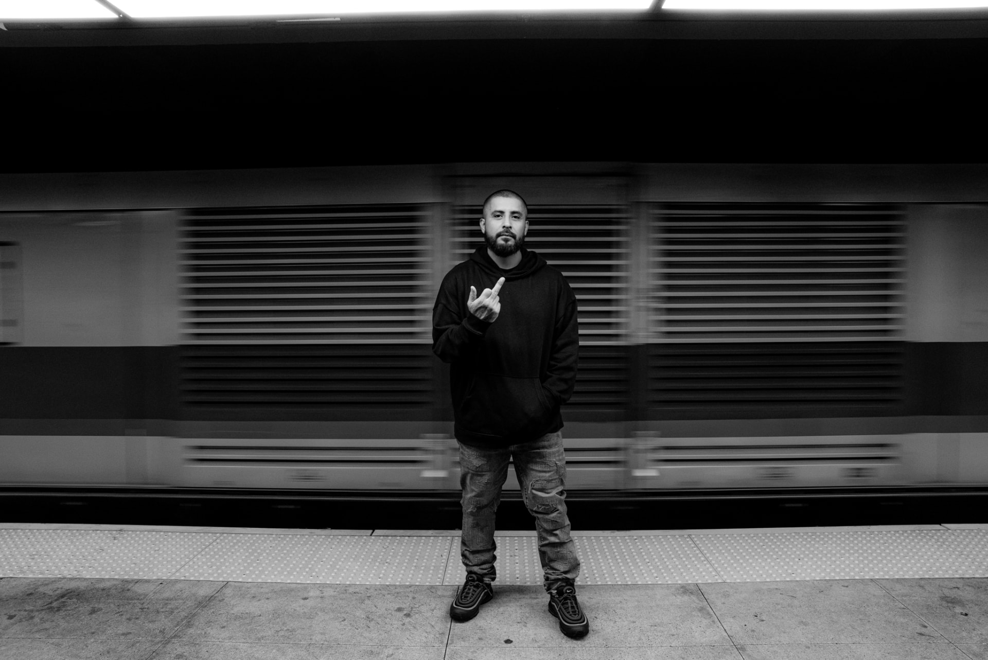 Black-and-white portrait on a subway platform with a train in motion