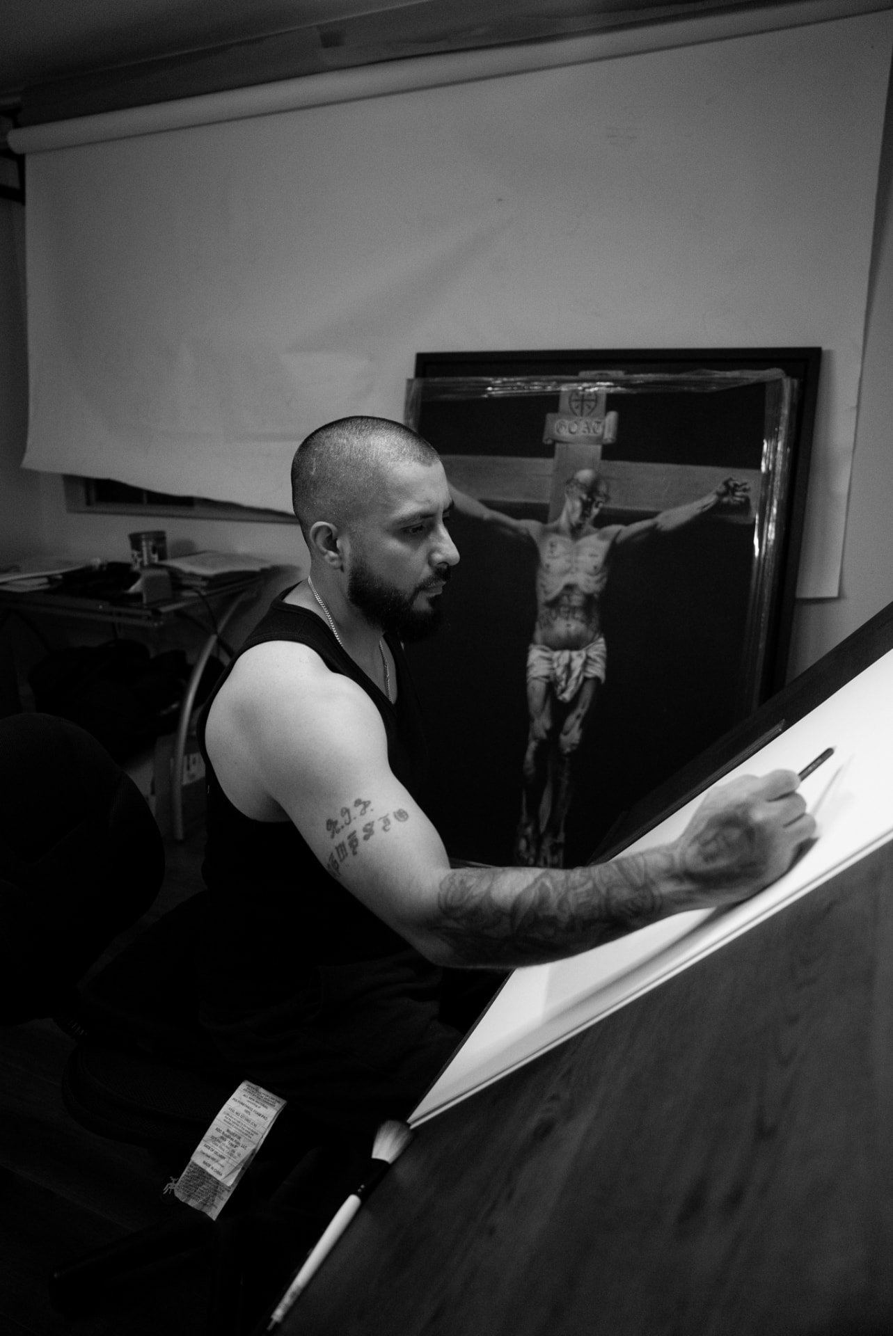 Black-and-white photo of a tattoo artist sketching at a drafting table
