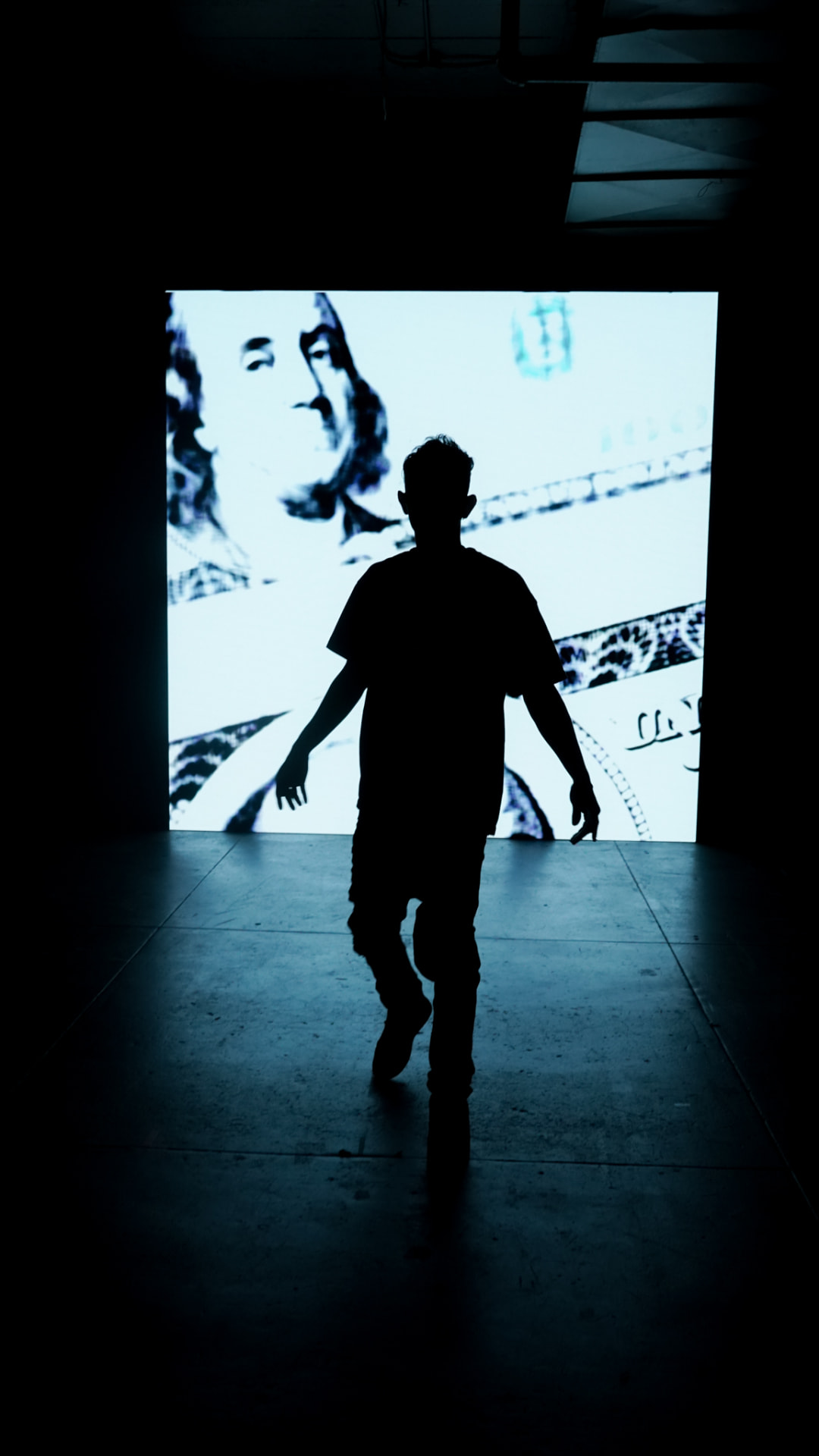 Silhouette of an artist walking in front of a bright projection