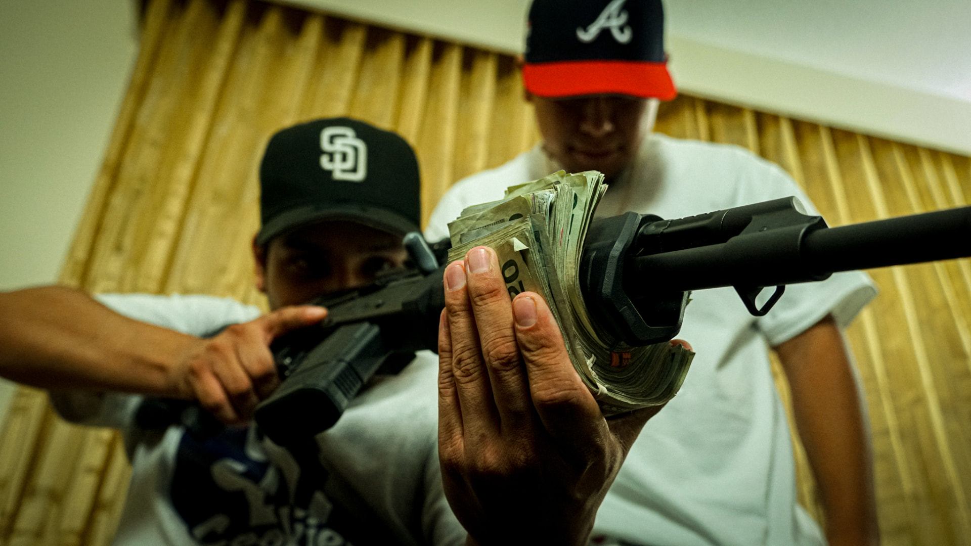 Two artists holding a stack of cash toward the camera