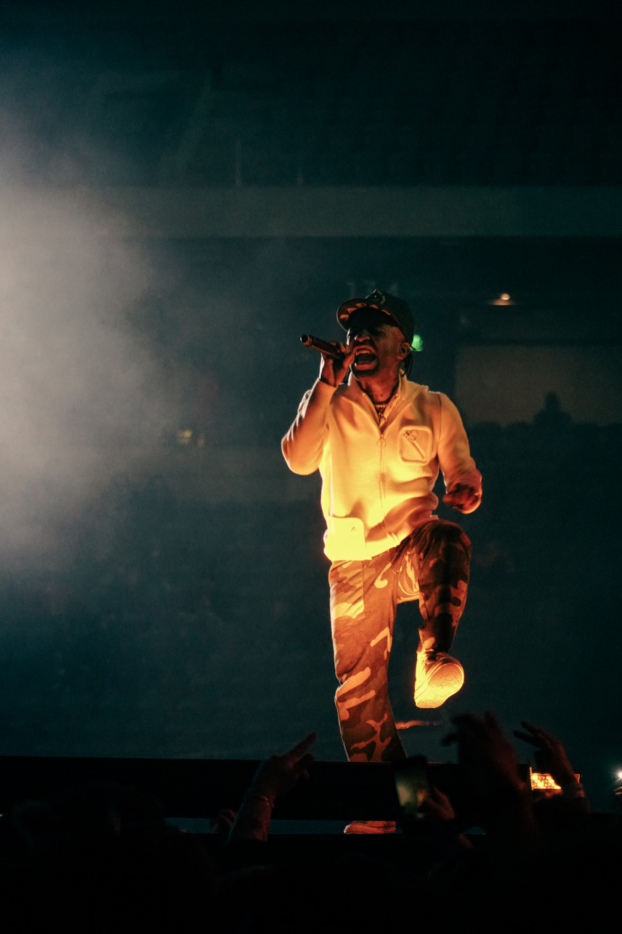 Performer on an arena stage lit by warm spotlight above the crowd