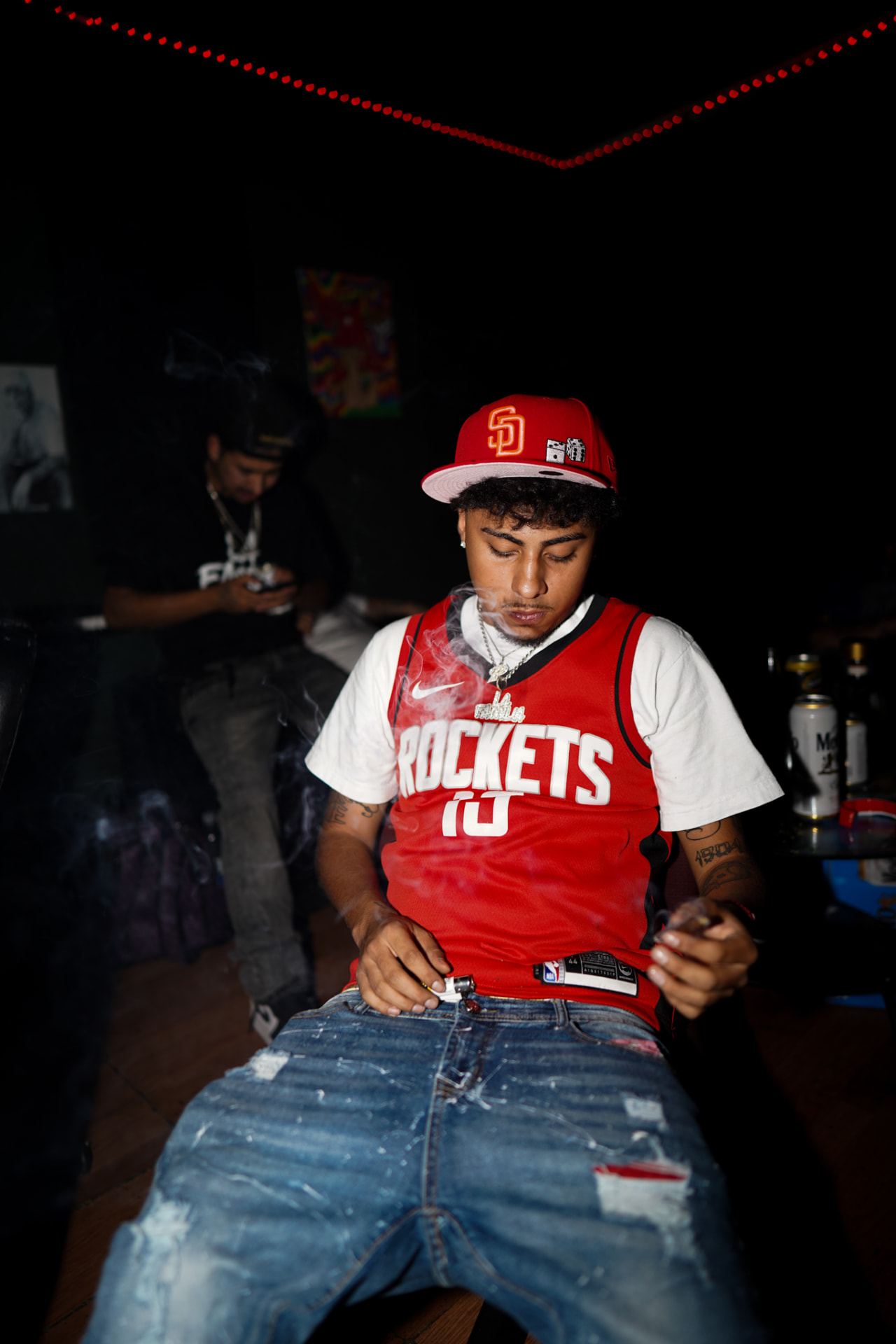 Artist in a red basketball jersey seated in a dim room