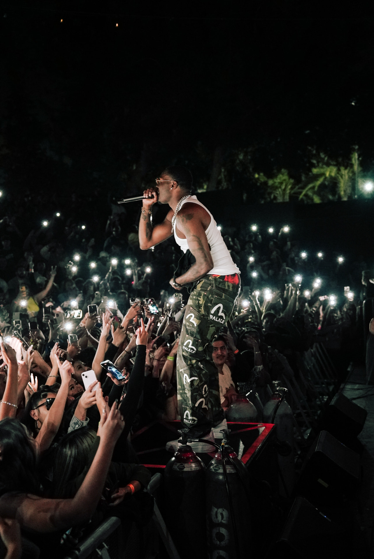 Performer singing above a crowd holding up lit phones