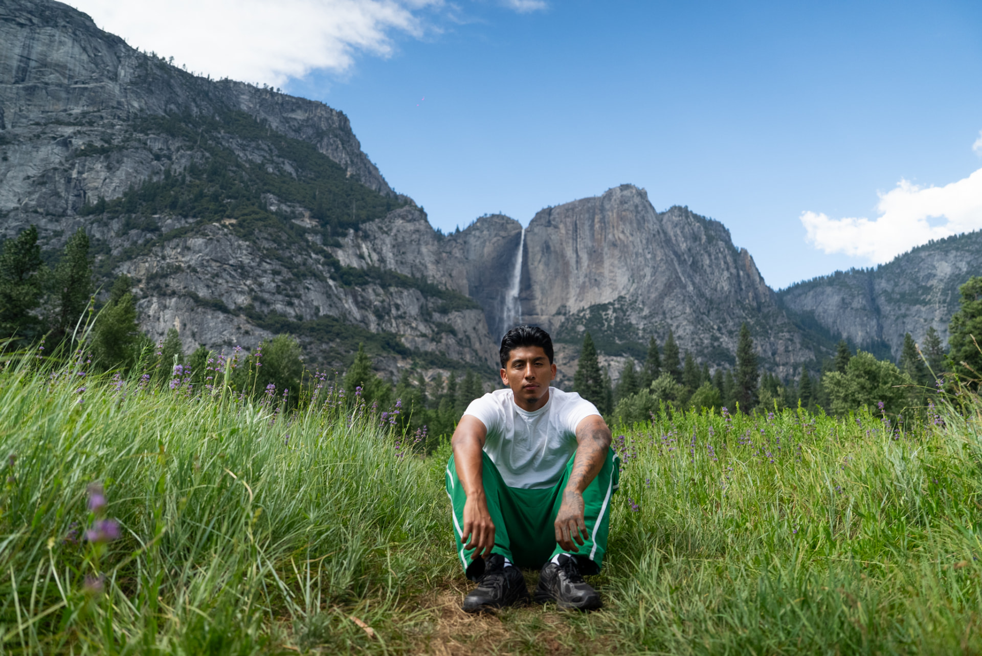 Louie Cannoy seated in a meadow beneath Yosemite Falls