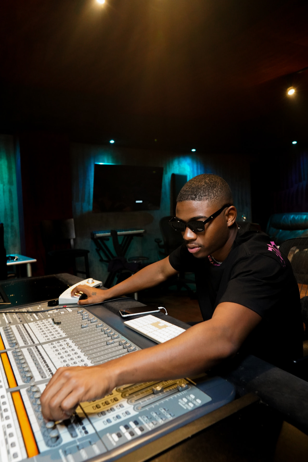 Producer working a large mixing console in a dim studio