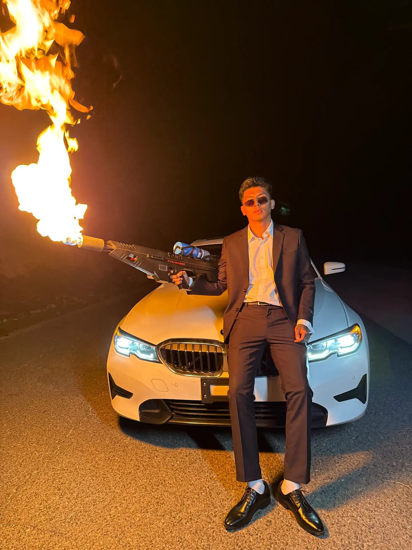 Suited up beside a white BMW with flames on set