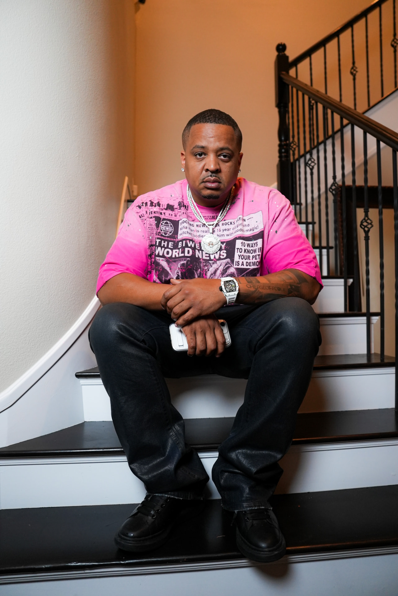 Artist in a pink graphic tee seated on an interior staircase