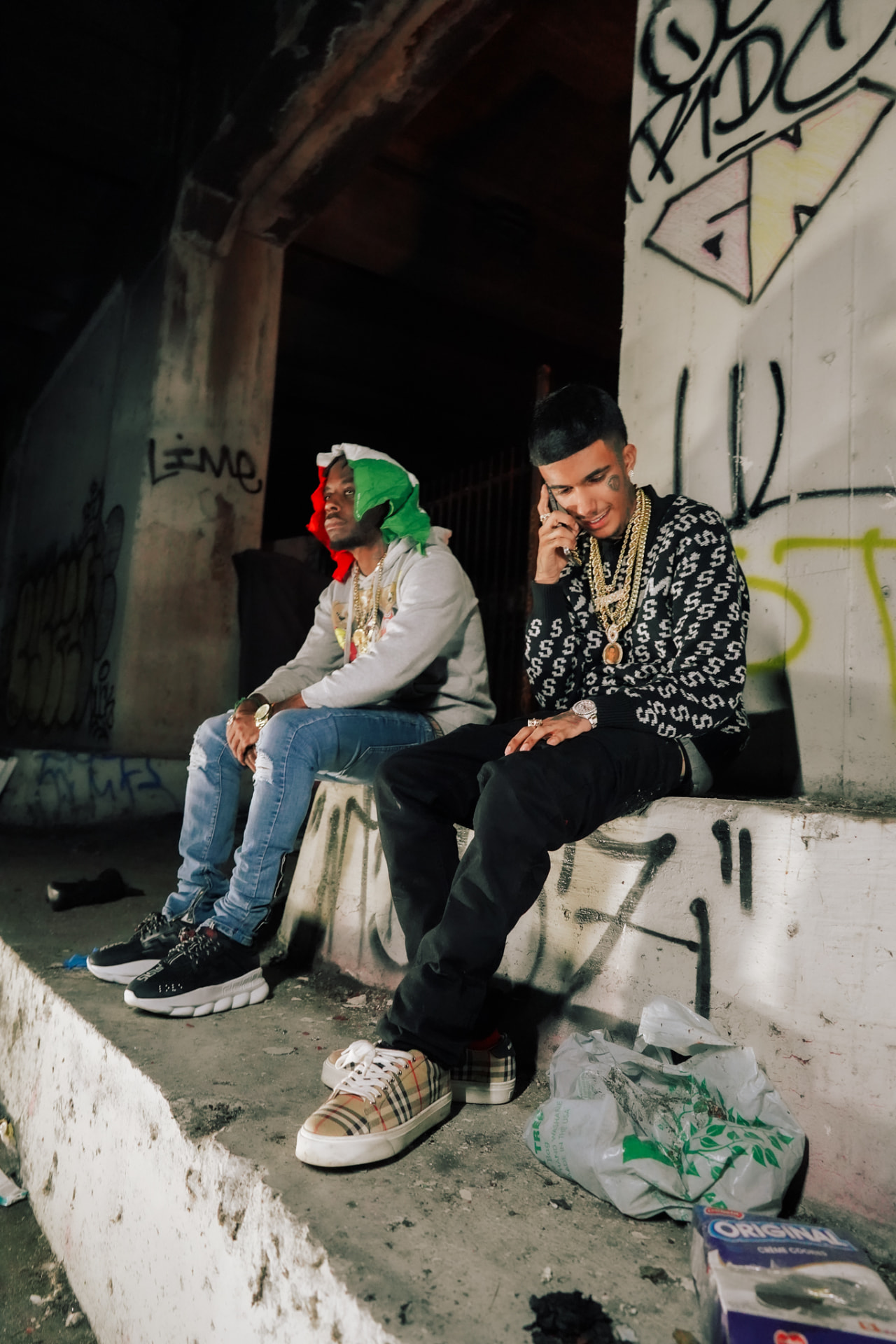 Two artists in chains seated on a graffiti-covered ledge