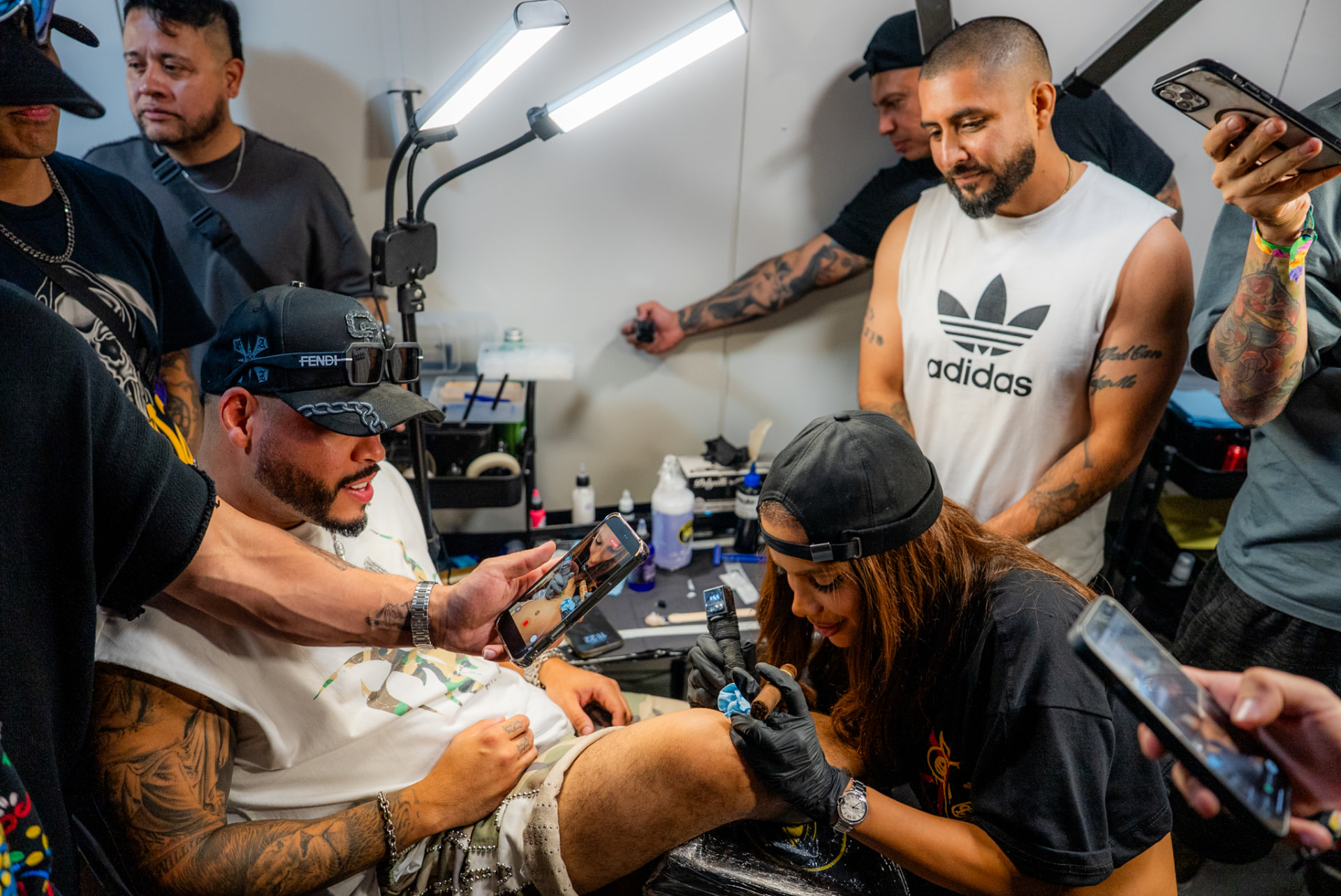Crowded tattoo convention booth during a leg tattoo session