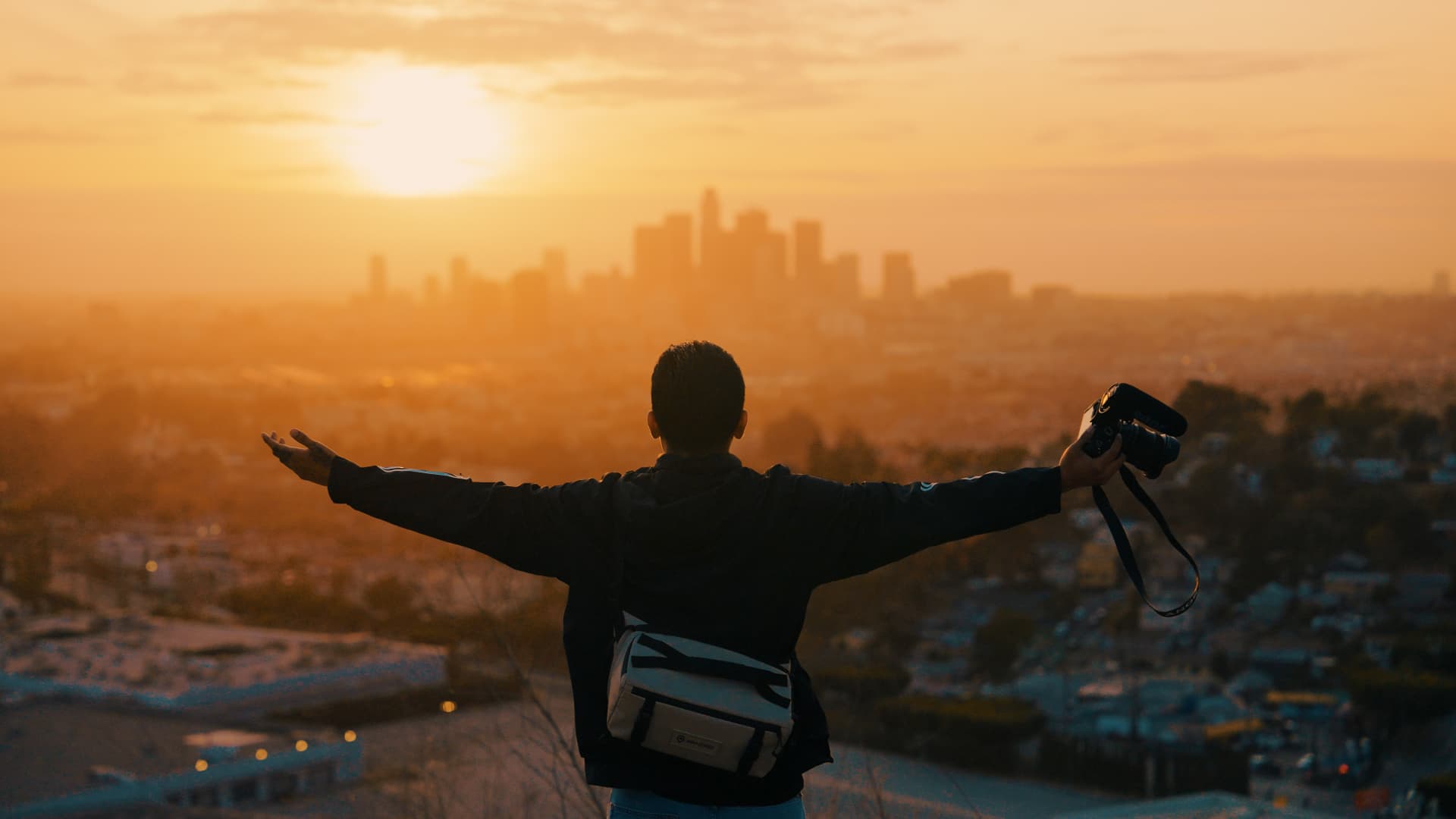 Arms open overlooking the Los Angeles skyline at sunset