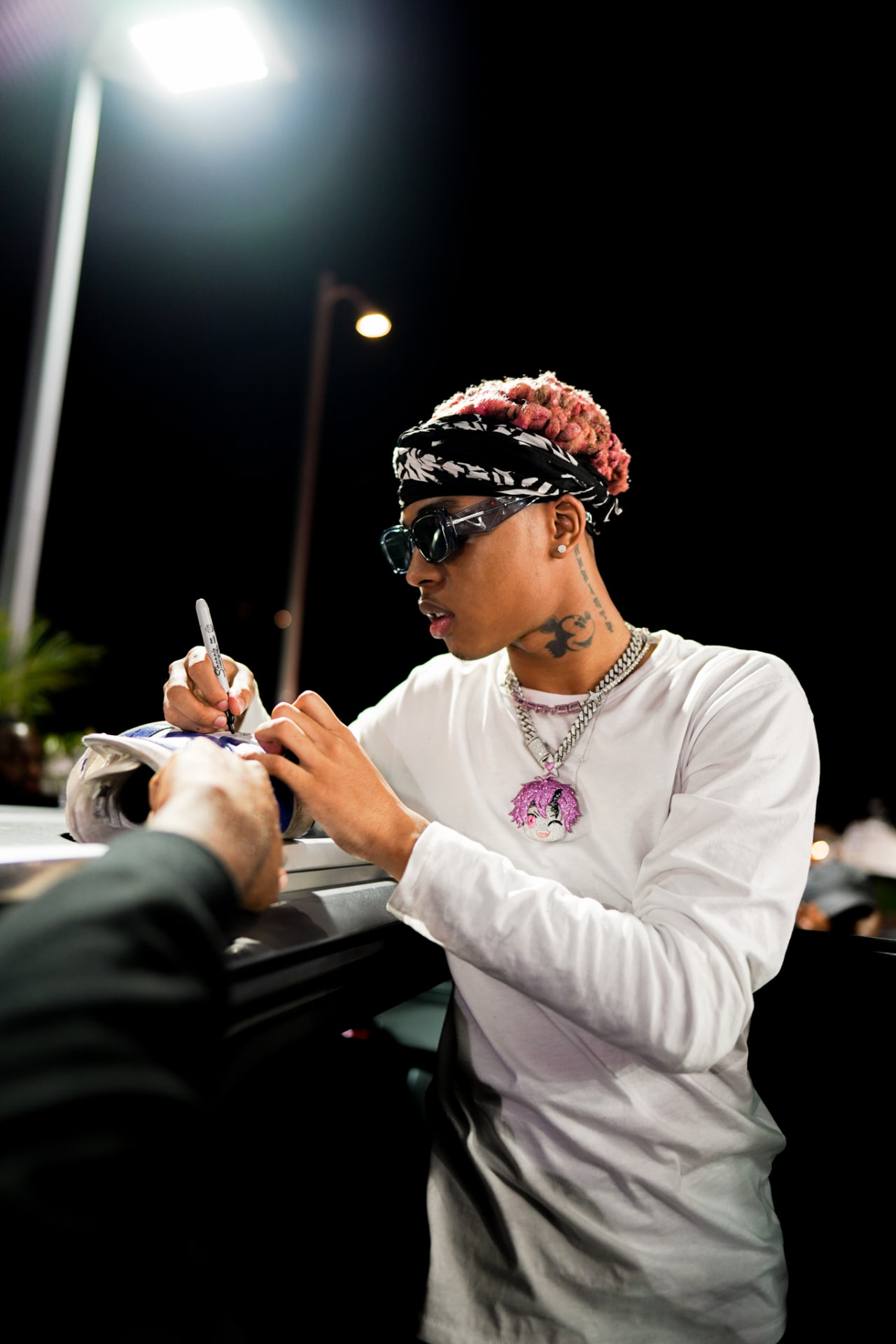 Artist signing a sneaker for a fan at night