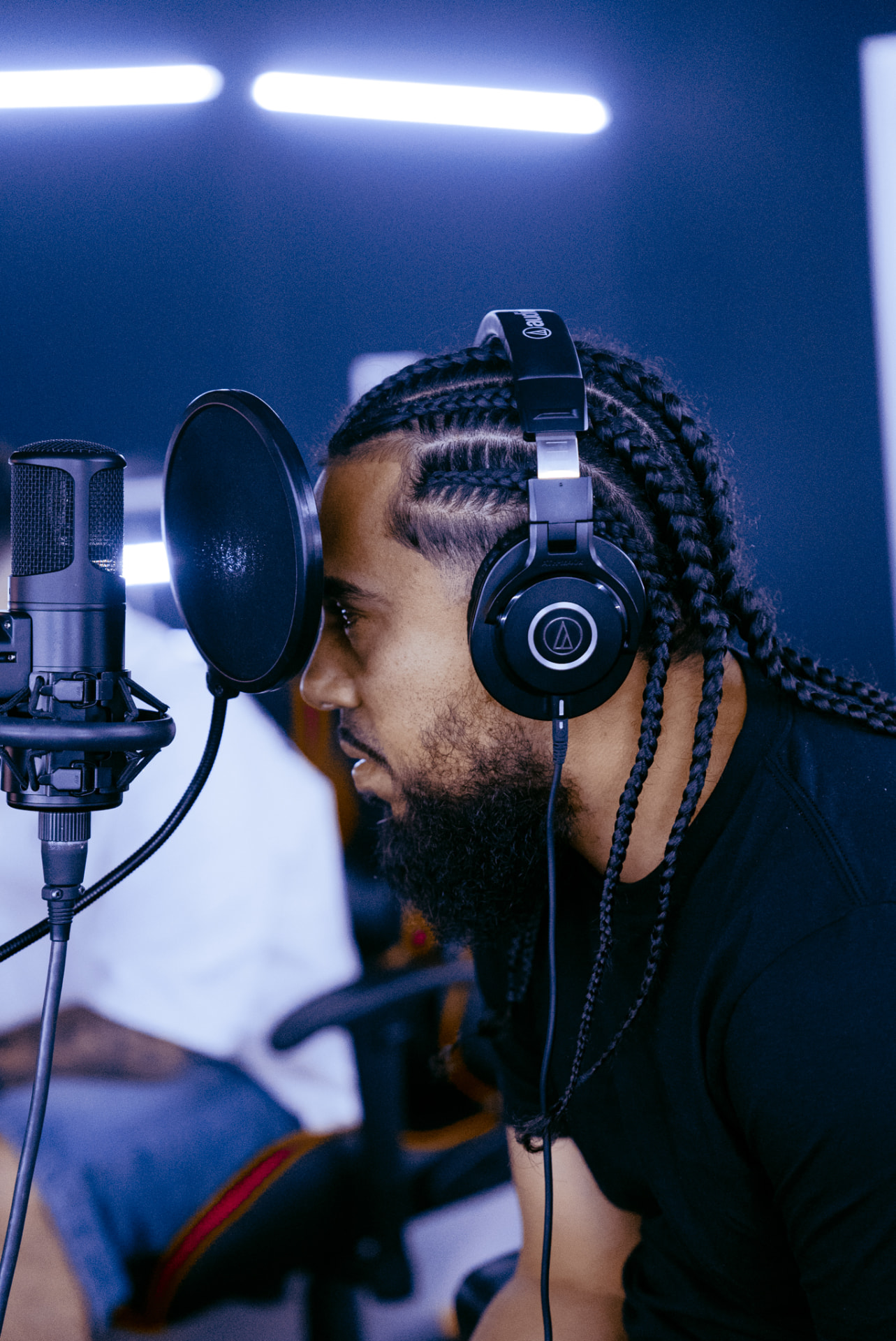 Artist recording vocals in a blue-lit studio booth